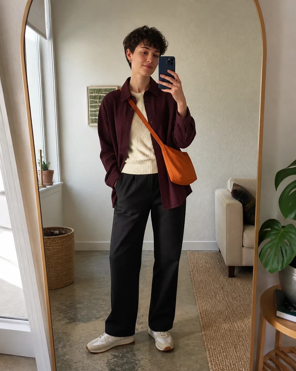 Persona mostrando un outfit de camisa ciruela, top claro y pantalón oscuro